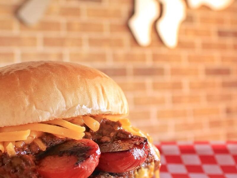A grilled chili cheese dog burger with cheddar
